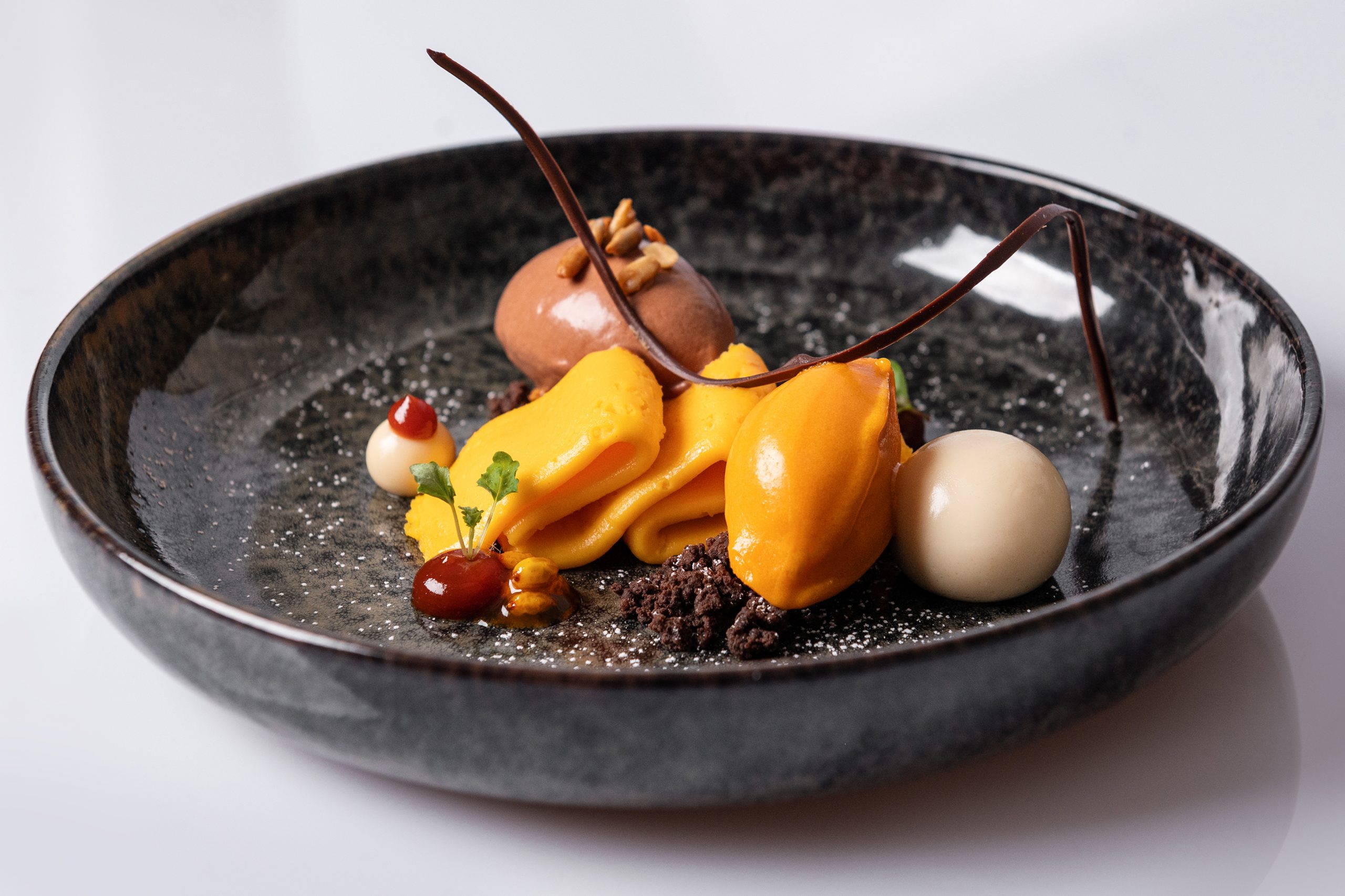 Rebers Pflug Restaurant Schwäbisch Hall-farbenfrohes Dessert mit Sorbet und Schokolade auf dunklem Teller