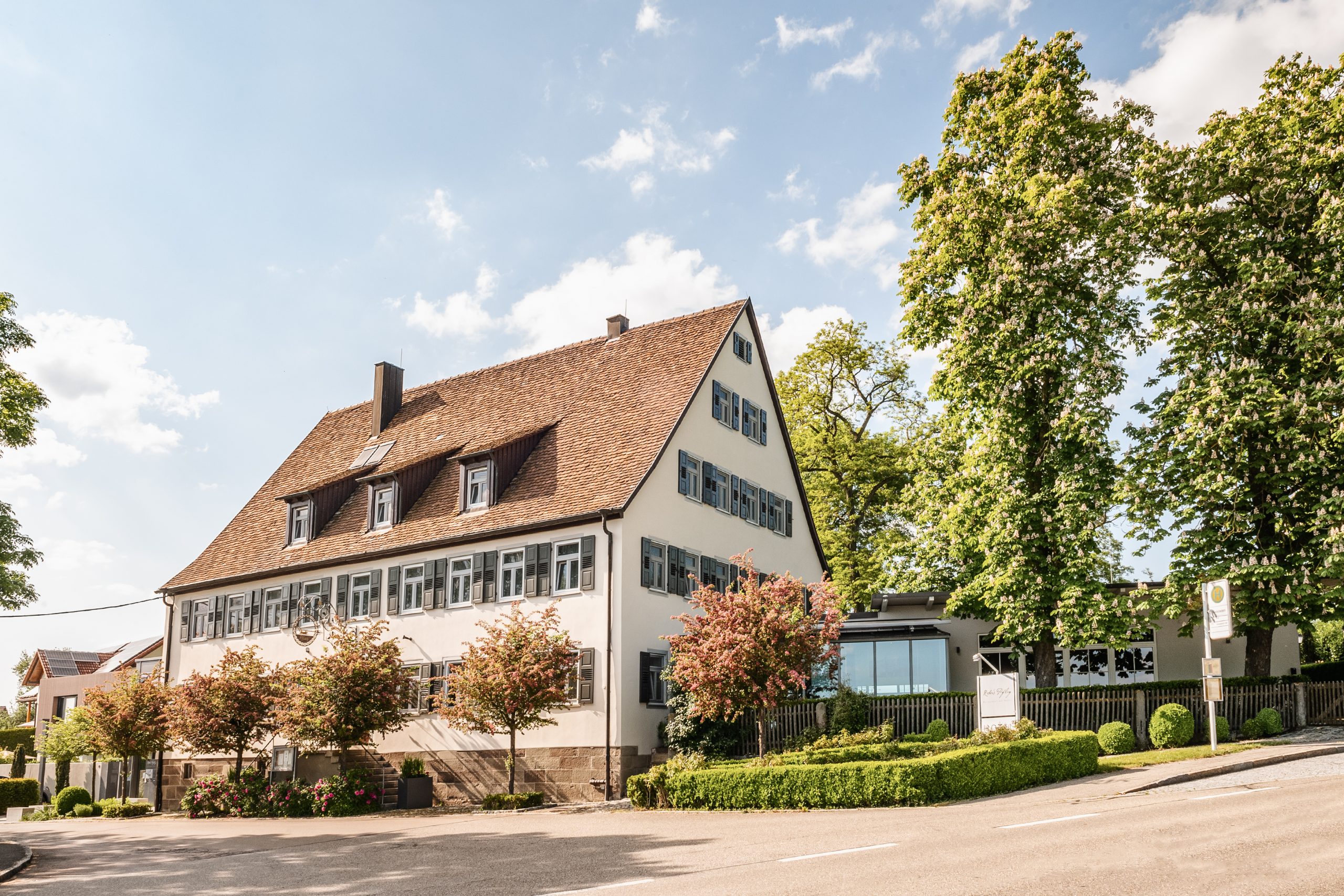 Rebers Pflug Hotel und Restaurant in Schwäbisch Hall-gepflegtes Landhaus mit Restaurantanbau bei strahlendem Sonnenschein und blauem Himmel